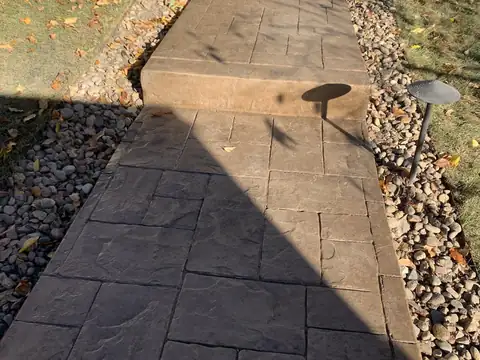 Curving stamped concrete walkway with low path lights and rock borders